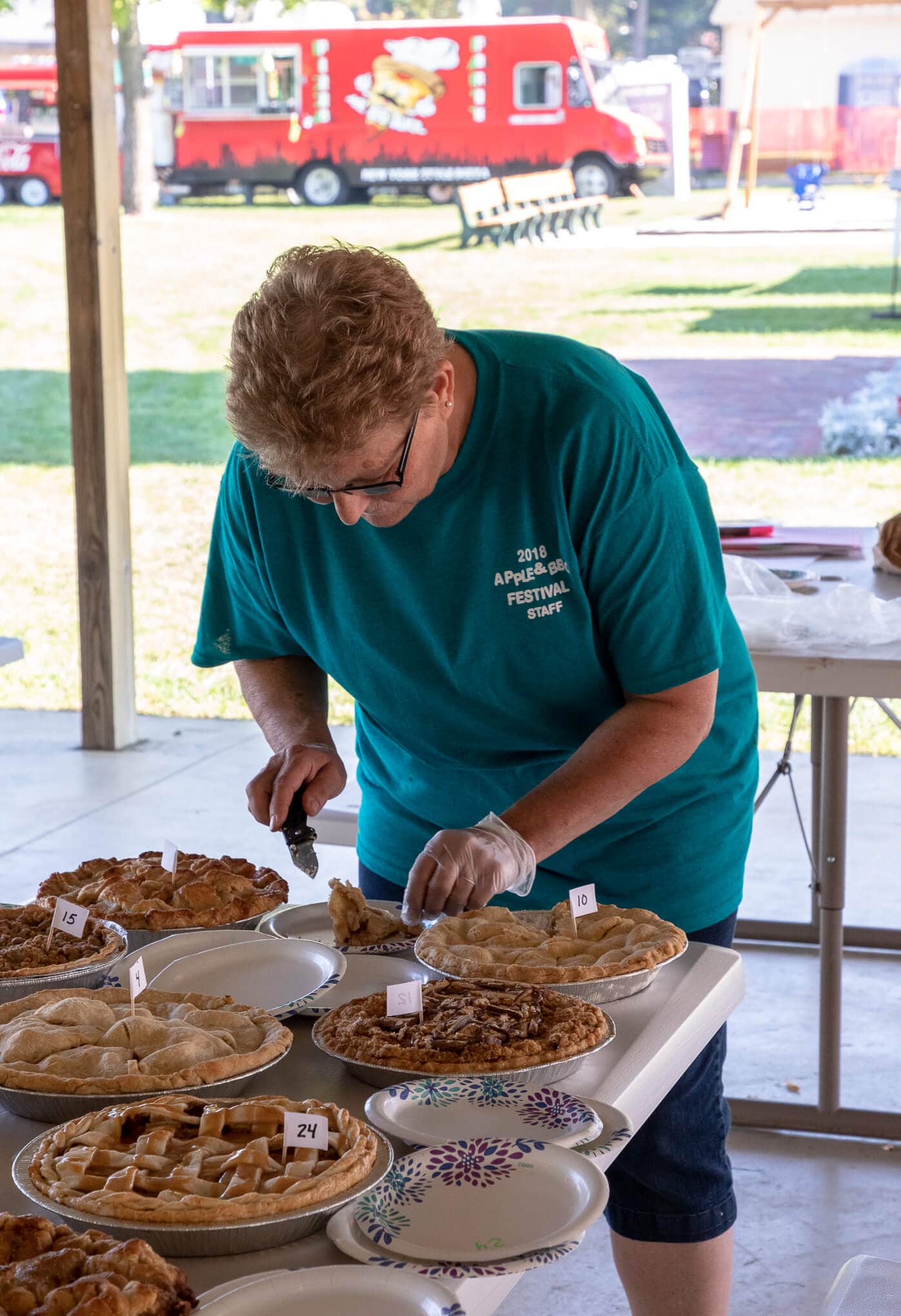 a woman cutting a piece of pie at the festival