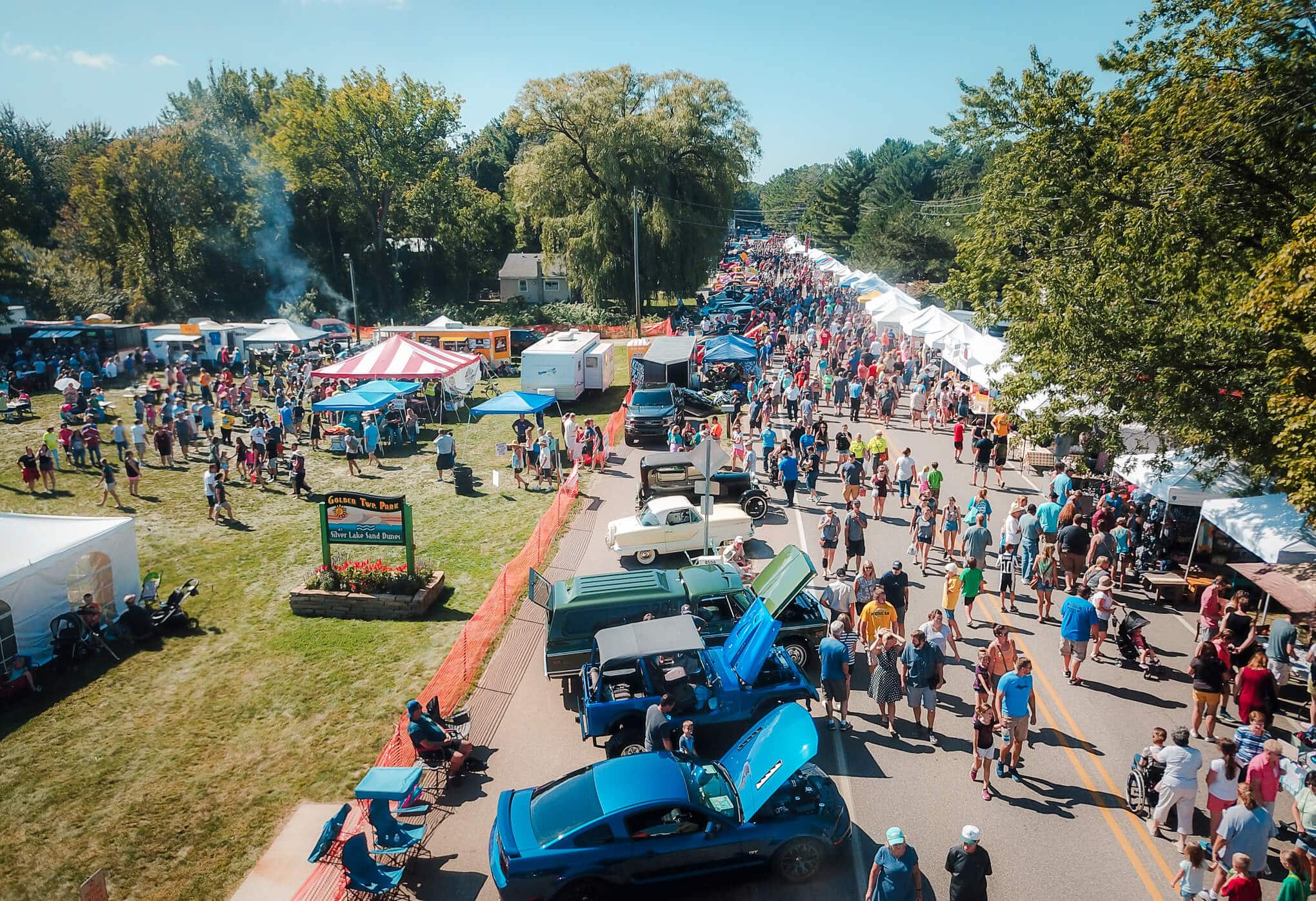 An aerial view of the festival and people looking and the cars and buying food